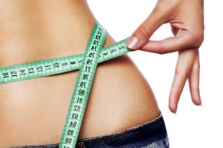 A woman is measuring her waist with a measuring tape