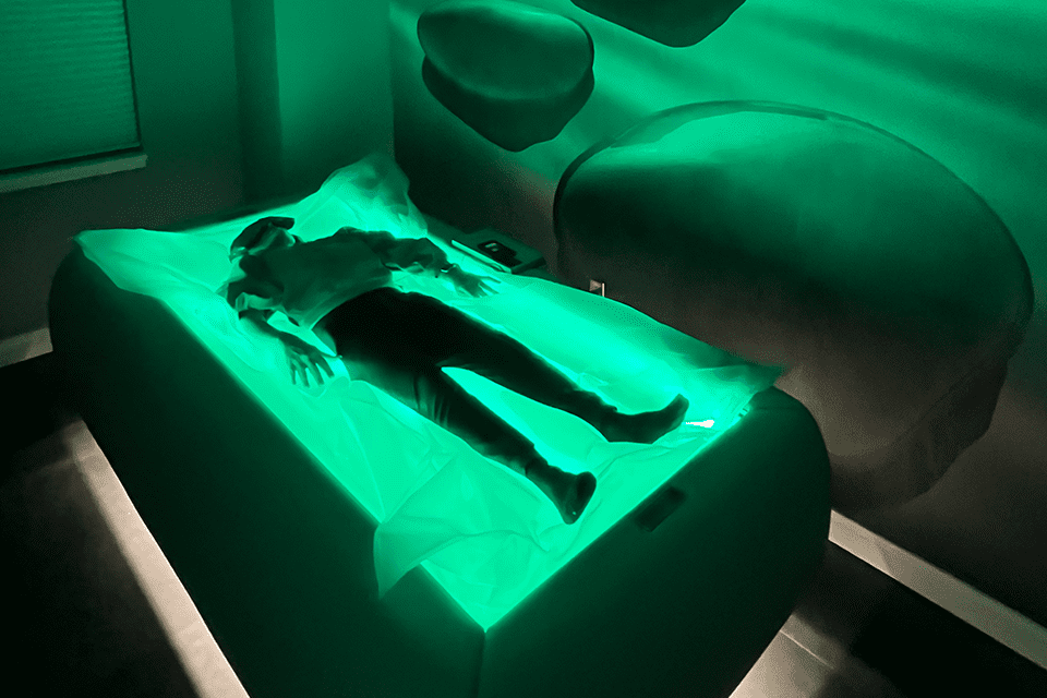 Person lying on a couch with green lighting.