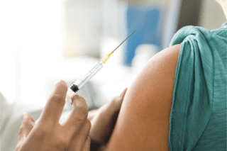 A person receiving a vaccination in the upper arm.