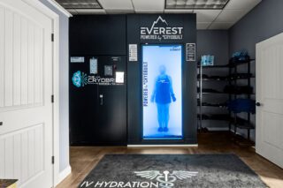 A person standing inside a cryotherapy chamber at a wellness facility.