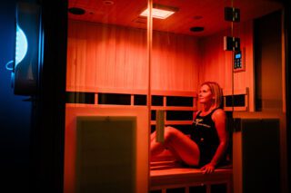 Woman sitting in an infrared sauna, looking to the side.