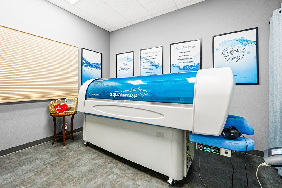 An aqua massage machine in a tranquil therapy room with calming wall art and warm lighting.