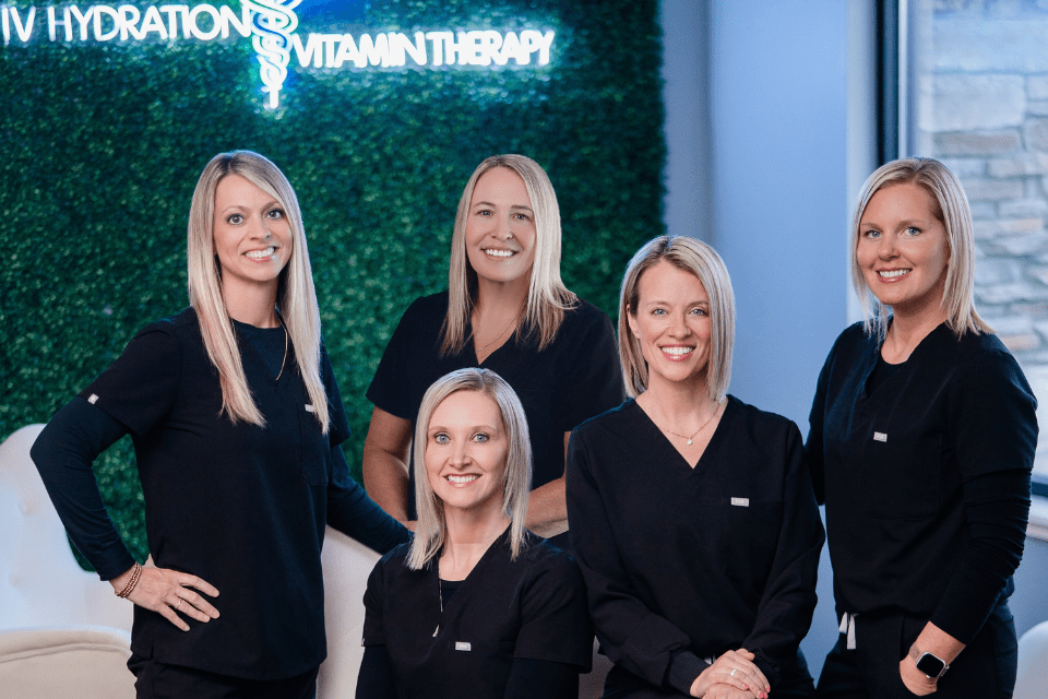 Four women in black scrubs smiling.